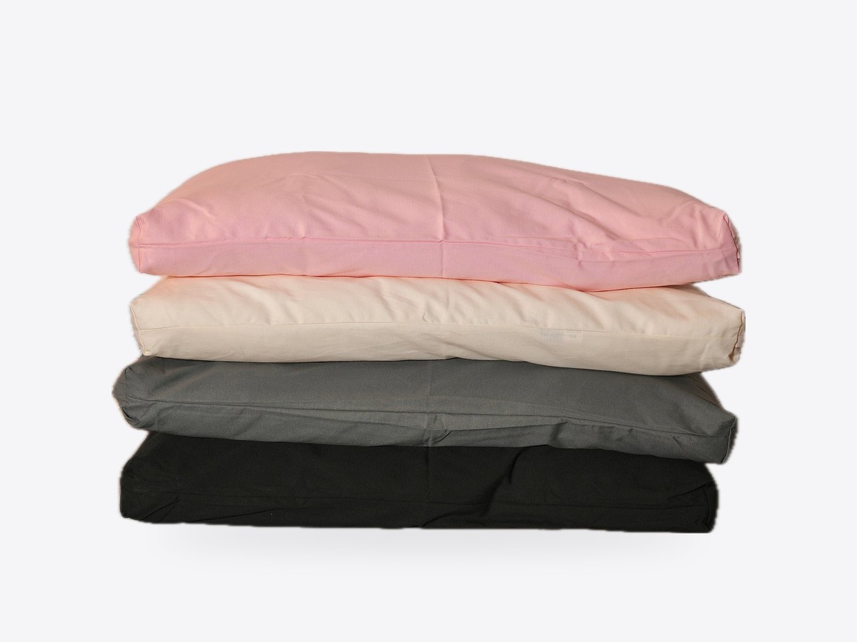 Four WLO cushions stacked in pink, cream, grey and black covers