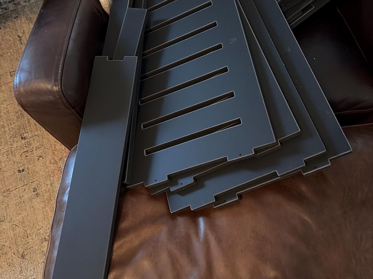 Matte black WLO Lakota panels stacked flat before assembly, with their CNC-cut tabs and slots